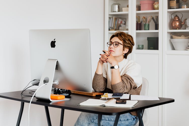 Focused Female Employee Reading Information On Computer In Office