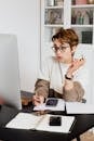 Surprising adult short haired female employee in eyeglasses reading unexpected information on computer and taking notes