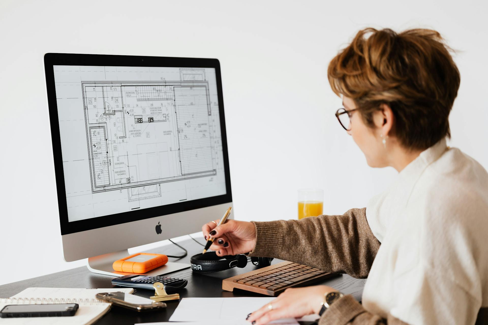 Side view of anonymous female employee in casual clothes and eyeglasses writing out information from computer while working at table in modern light office