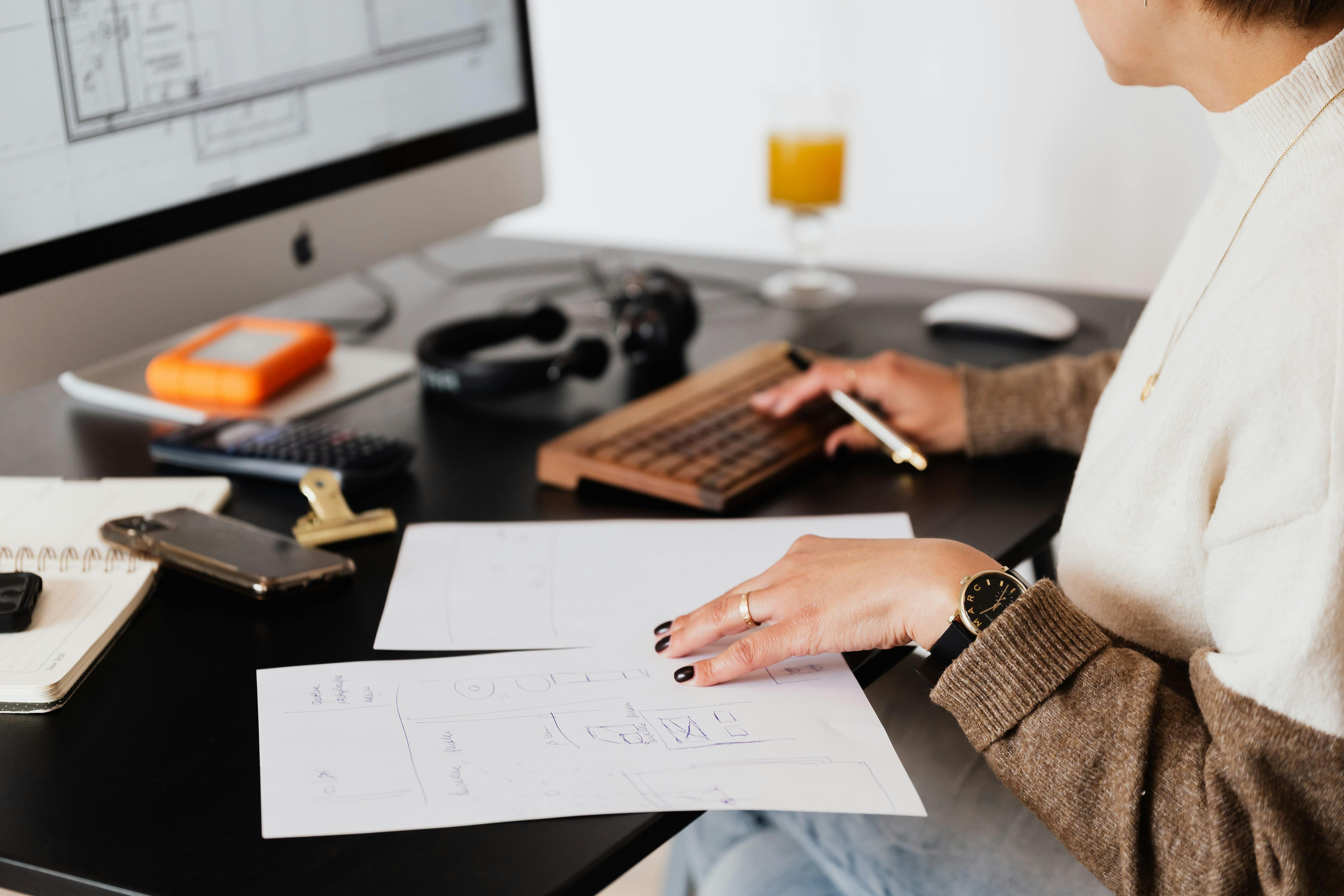 crop anonymous woman working with documents sitting at table with computer