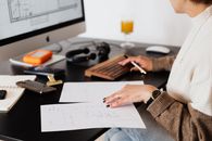 女企业家在办公室工作期间检查文件并打字时的侧视图，未露面部