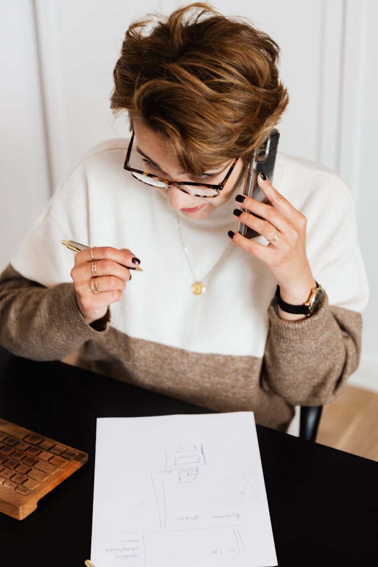 Female Interior Designer Talking On Cellphone And Making Sketchy Plan