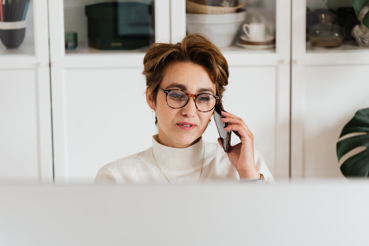 Smart Woman In Eyeglasses Having Phone Conversation In Modern Office