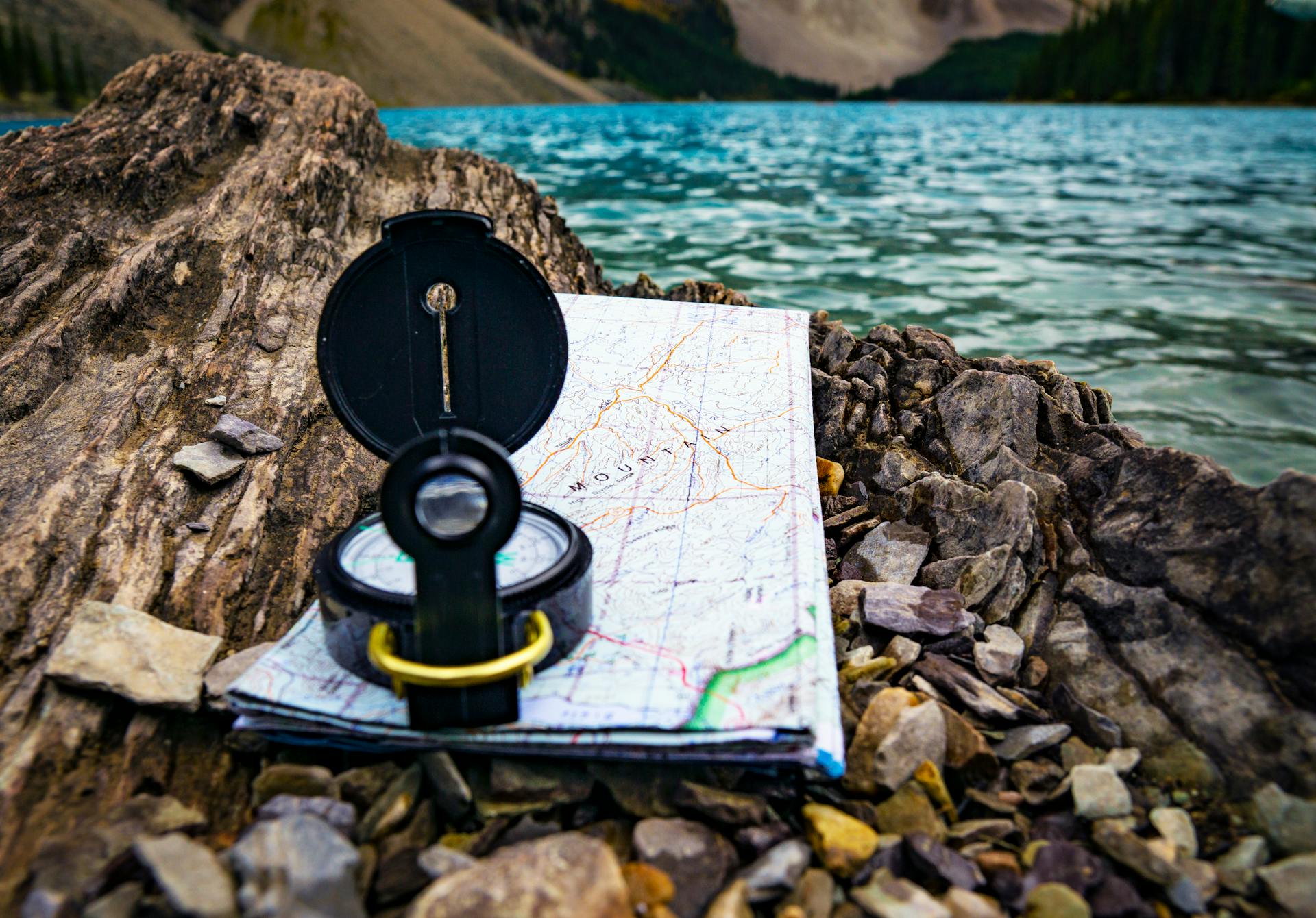 Compass and map on rocky lakeside, perfect adventure and travel imagery in the Canadian wilderness.