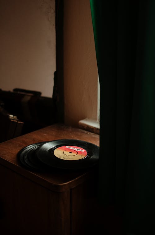 Free High angle of vinyl discs with colorful sticker placed on old wooden cabinet in vintage studio Stock Photo
