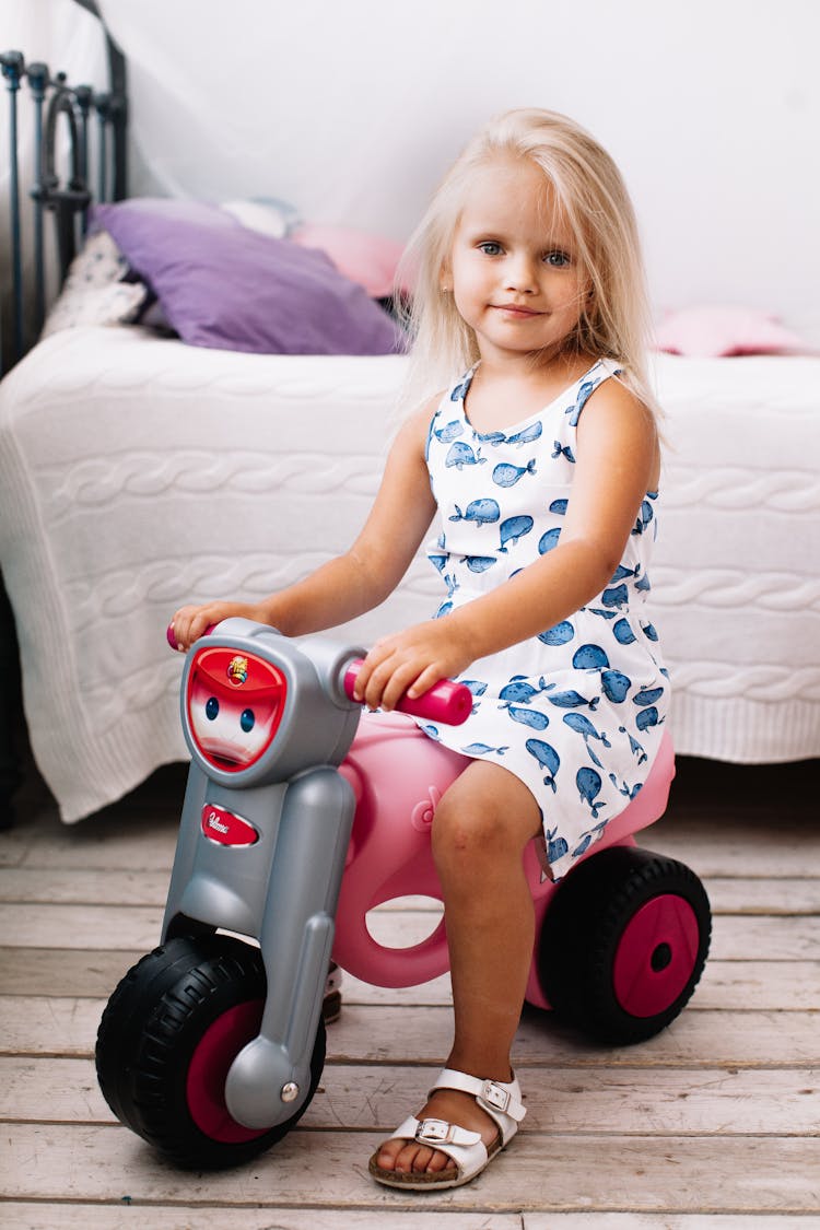 Girl In Blue And White Tank Dress Riding On A Toy Motorbike