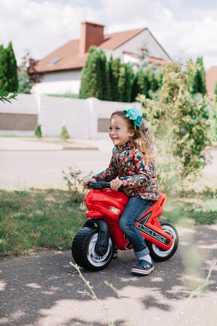 Girl Riding On Red Toy Motorbike