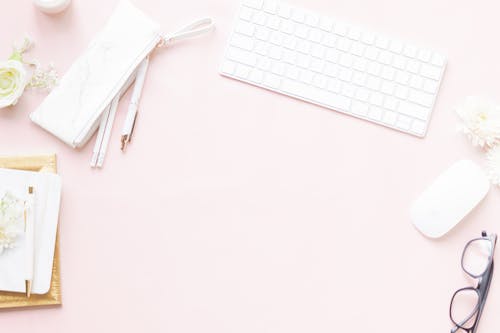 White Keyboard and Computer Mouse Beside Pens and Eyeglasses on Pink Surface