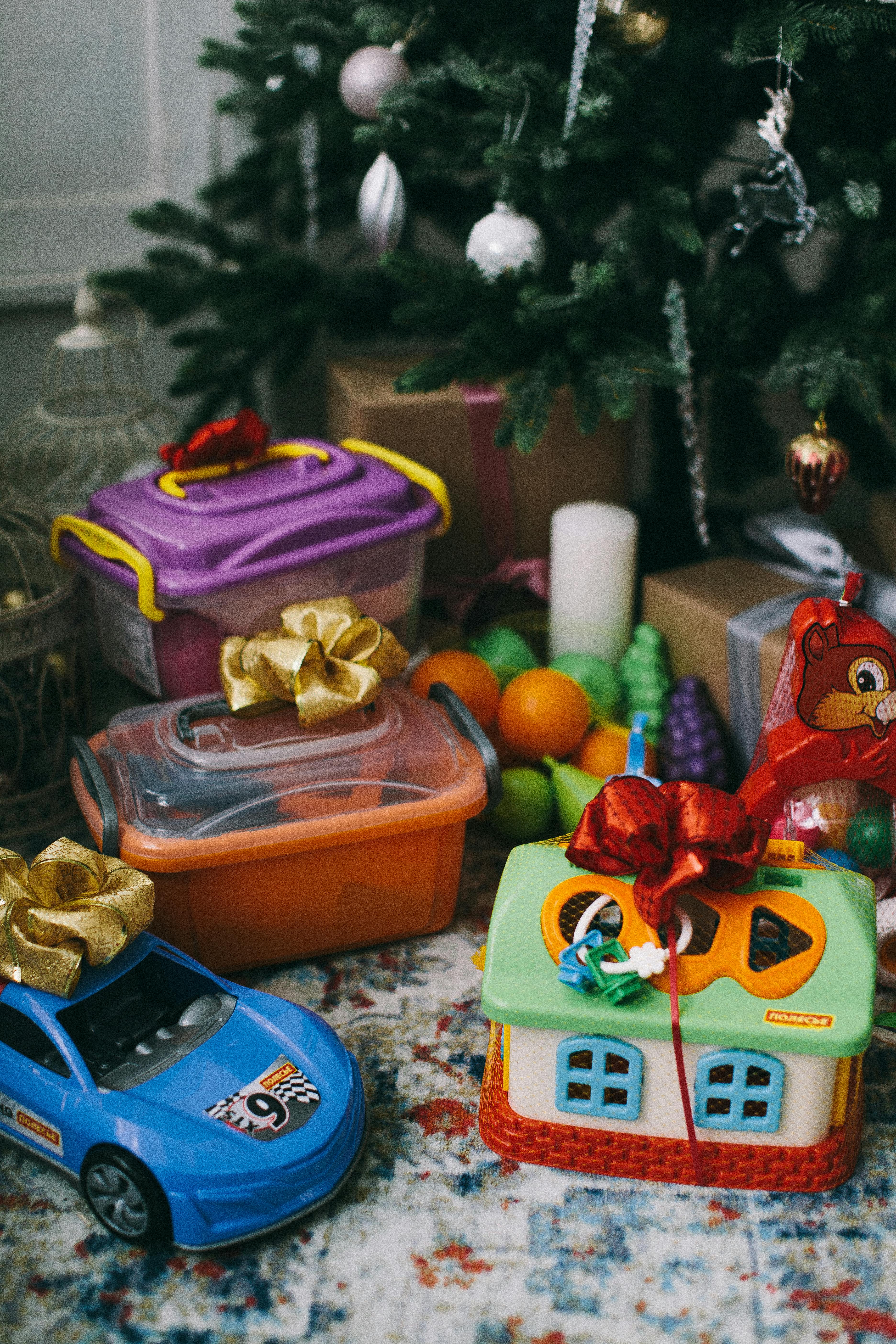 assorted plastic toys under a christmas tree