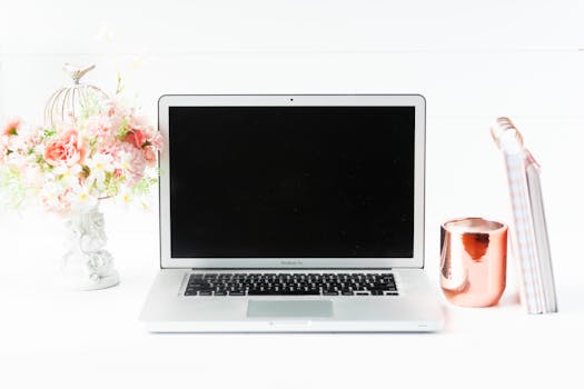 A sleek workspace featuring a laptop, floral arrangement, and copper mug for a modern aesthetic.