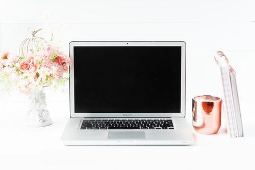 Free A sleek workspace featuring a laptop, floral arrangement, and copper mug for a modern aesthetic. Stock Photo