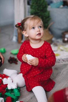 穿着红色连衣裙的可爱幼儿在室内玩着五颜六色的积木