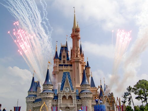 Amazing princess castle with colorful ornamental details located in amusement park during fireworks