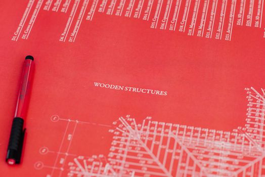 Close-up of a red architectural blueprint showcasing wooden structures.