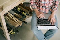 工匠在木工车间使用笔记本电脑，专注于在线研究或设计