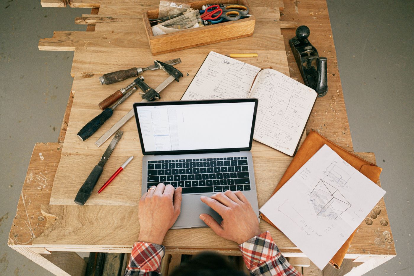 Carpentry workbench with laptop plans tools and handwritten job notes