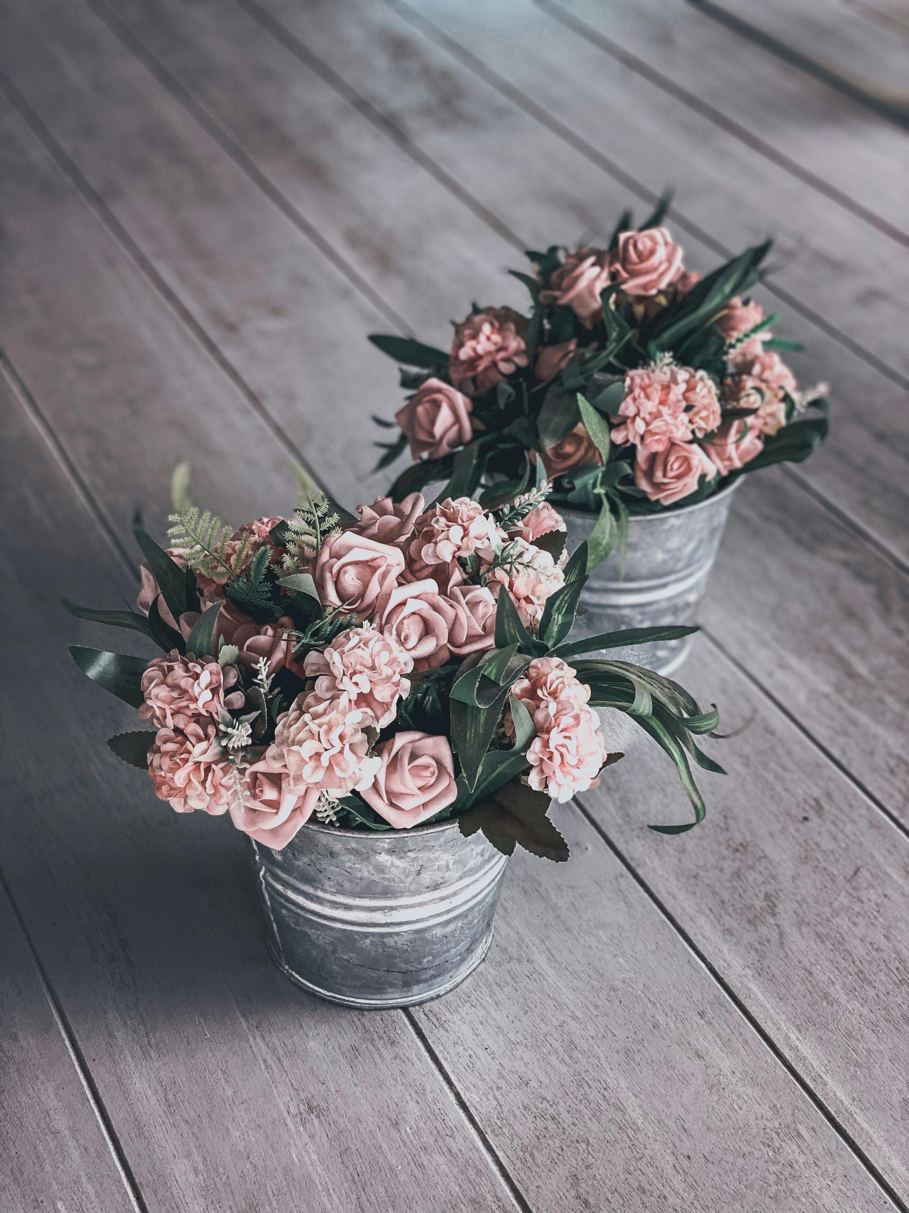 木地板上，乡村金属桶里插着迷人的粉红色玫瑰和康乃馨