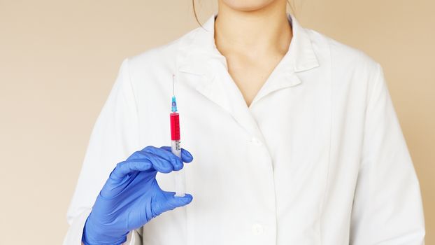 一名穿着医用制服和乳胶手套的女护士，手里拿着注射器准备接种疫苗