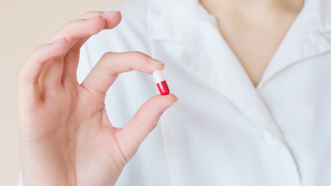 Free Crop nurse demonstrating small double colored pill Stock Photo