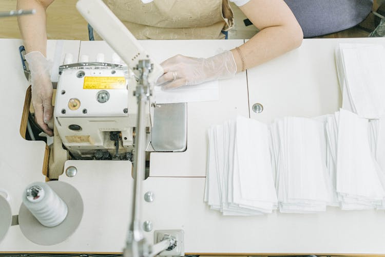 Hands Of A Person Wearing Gloves Using A Sewing Machine