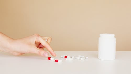 Crop patient taking pill from table