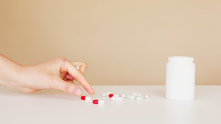 Crop Patient Taking Pill From Table