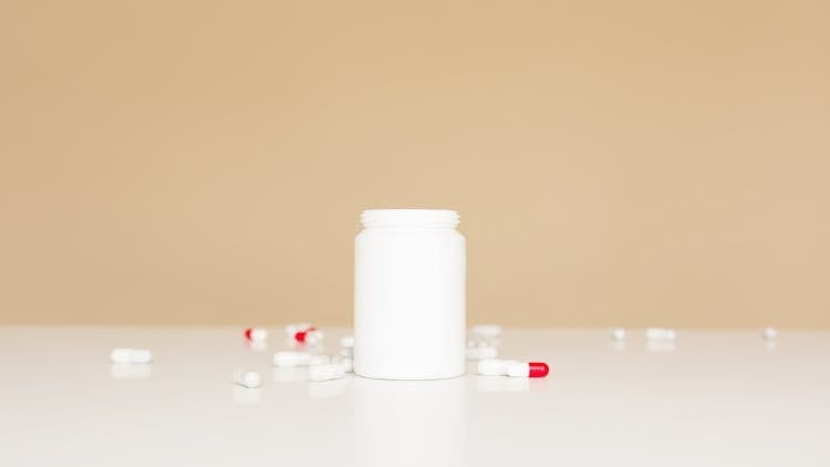 Open Bottle And Pills Scattered Around On Table