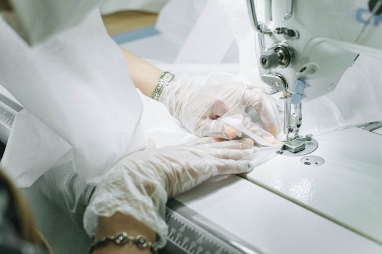 Person Wearing Plastic Gloves Using A Sewing Machine