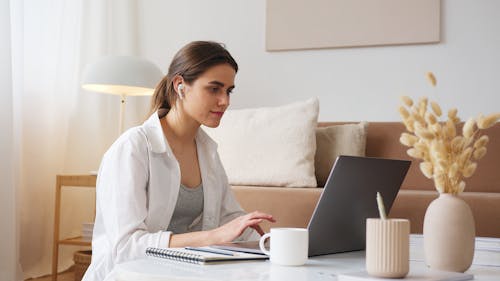 Free Thoughtful woman with earbuds using laptop Stock Photo