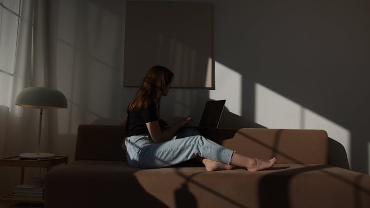 Woman With Laptop Sitting On Couch