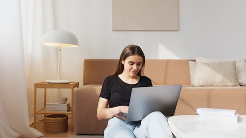 Glad young woman working on laptop in living room