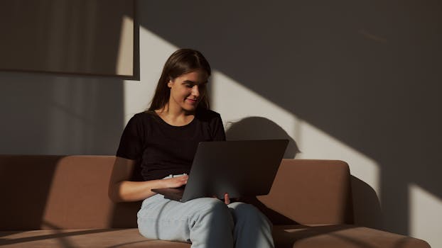 Casual woman enjoying free time browsing laptop on sofa indoors.