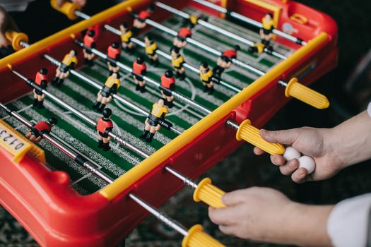 Close-up of hands playing a foosball game, capturing the thrill of table soccer indoors.