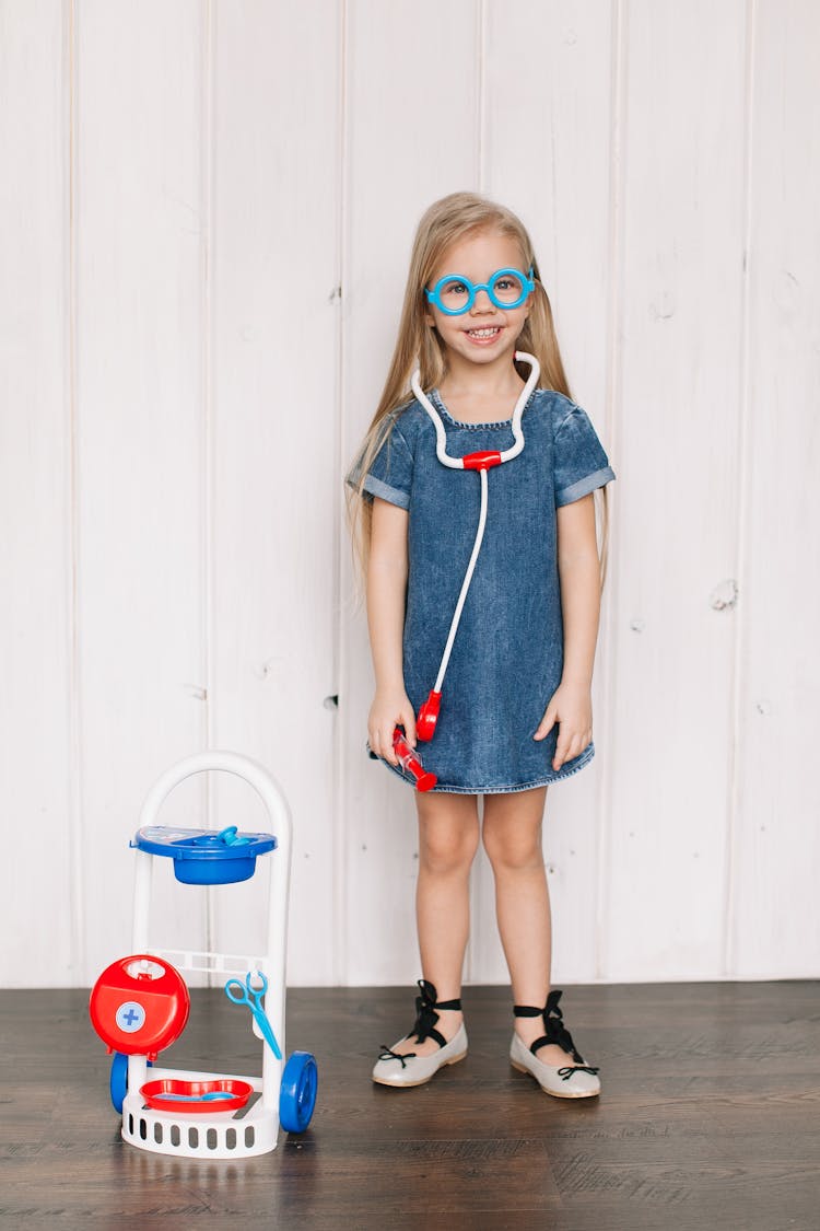 Girl In Denim Blue Dress Holding A Toy Stethoscope