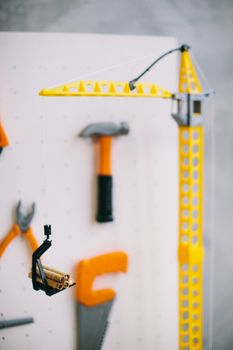 Close-up view of a yellow toy construction crane with hanging tools and construction pieces.