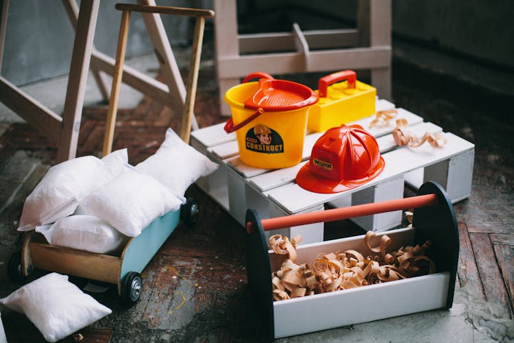 Wood Shavings In A Toolbox Near Plastic Toy Bucket And Hard Hat