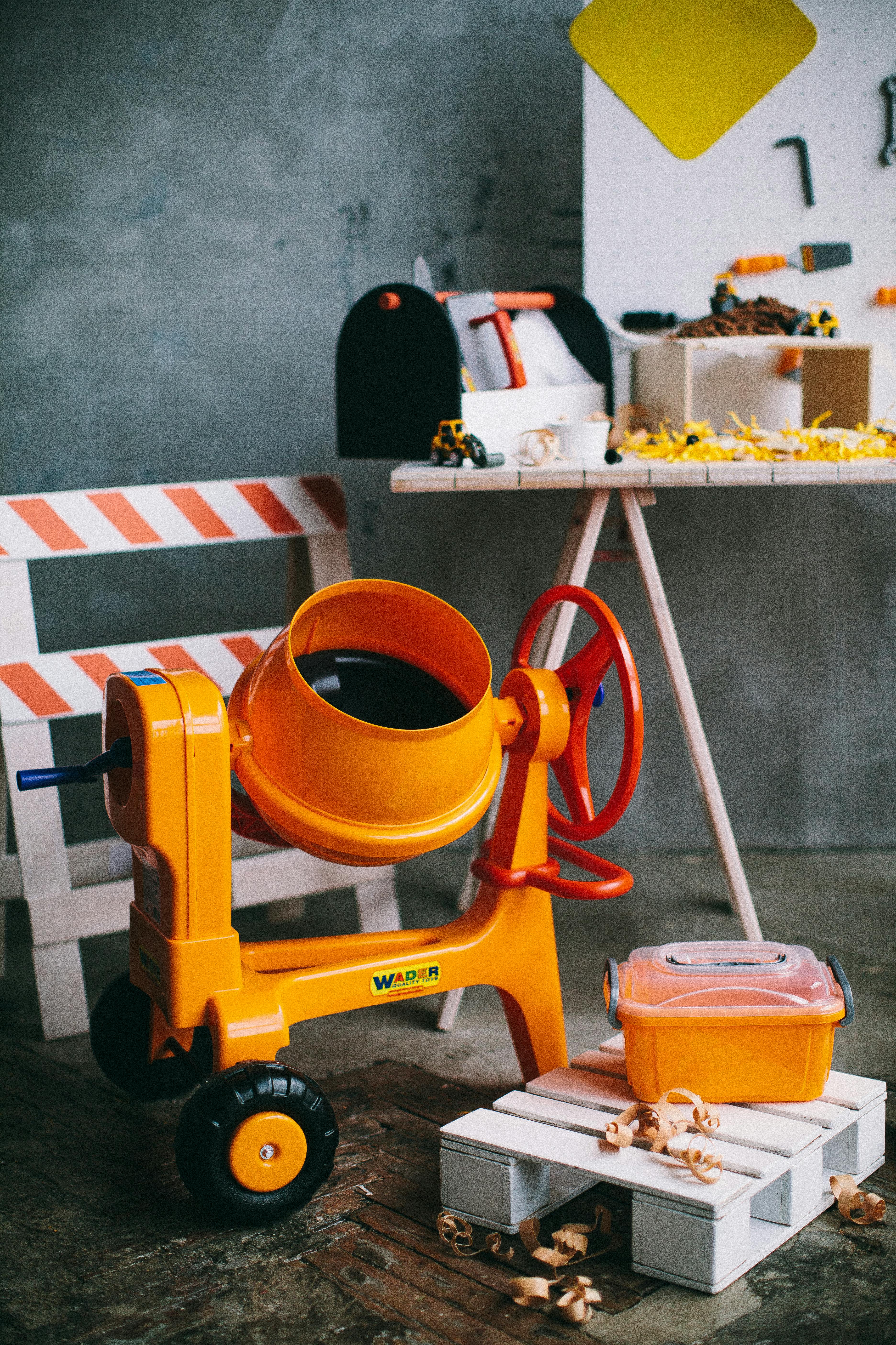 Colorful toy construction set featuring an orange cement mixer and tools.