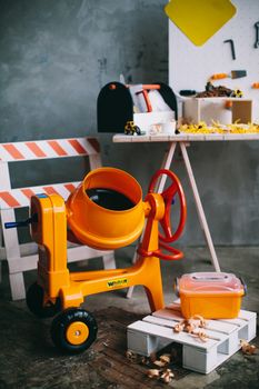 这套五颜六色的玩具建筑套装，配有橙色水泥搅拌机和工具