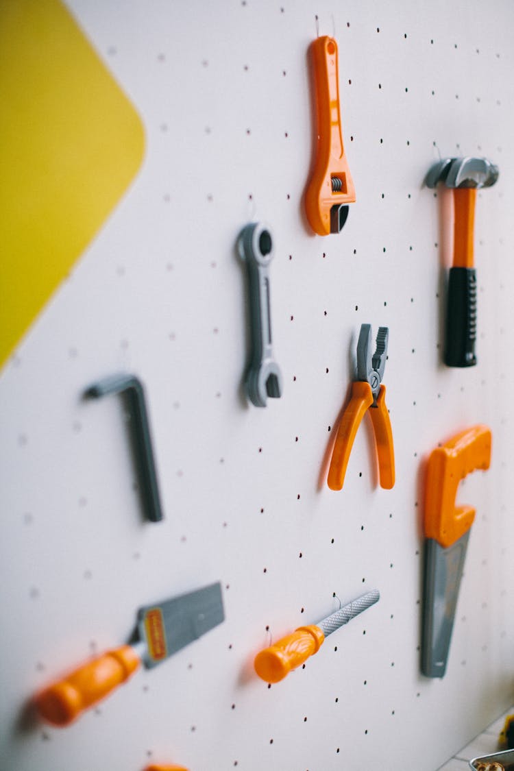 Orange And Gray Plastic Toy Tools On A White Pegboard