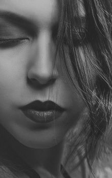 Intimate black and white close-up of a woman's face with eyes closed, capturing serene elegance.