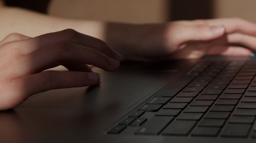 Free Hands of anonymous person using touchpad of laptop while sitting at table at home Stock Photo