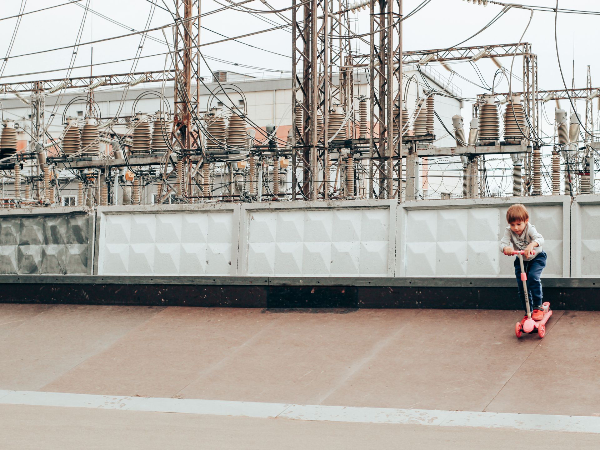 Little child practicing kick scooter near power plant