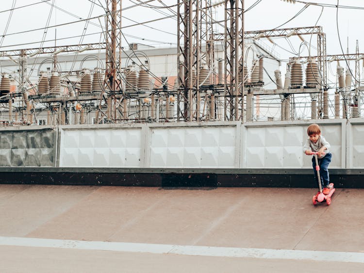 Little Child Practicing Kick Scooter Near Power Plant