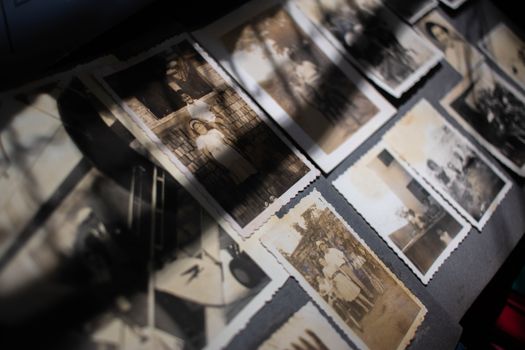 Vintage sepia photographs scattered on a surface, highlighting light and shadow contrast.