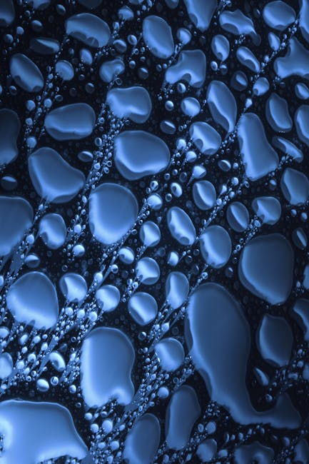 Top view closeup of water drops of various shapes spread on blue surface as abstract background