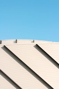 Architectural detail of a modern stadium facade with a repetitive pattern against a vivid blue sky.