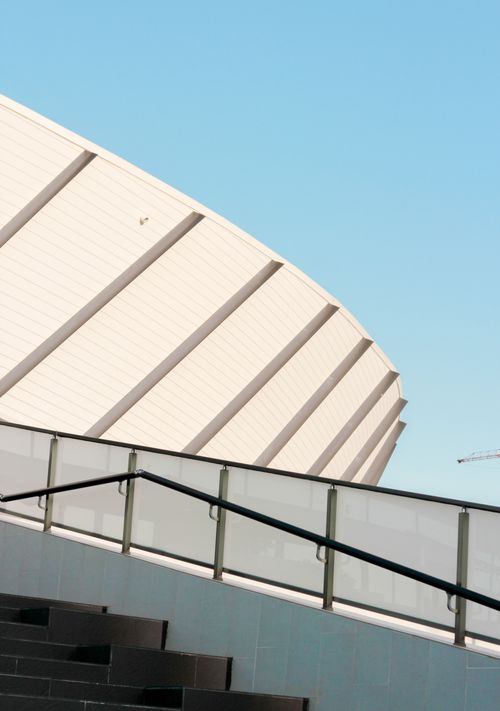 Free Contemporary stadium facade with a clear blue sky in contrast, showcasing sleek design elements. Stock Photo