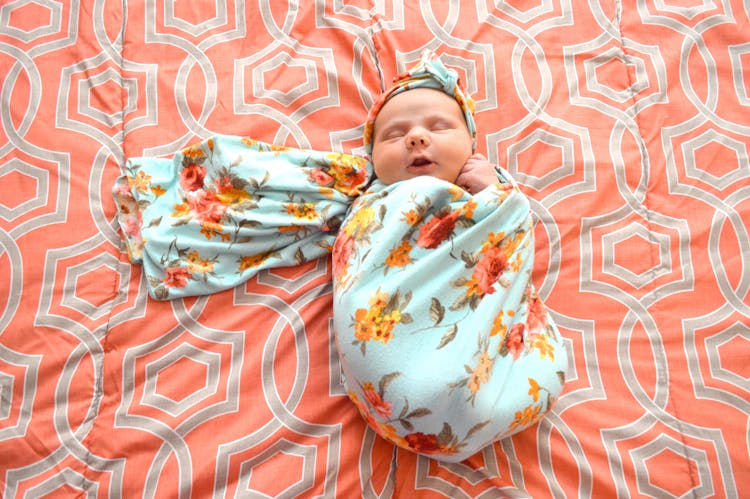 A Baby Wrapped In A Floral Blanket