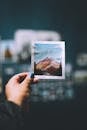 Person Holding a Photograph of a Mountain