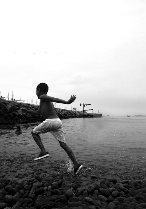 A Shirtless Boy Wearing Shorts and Rubber Shoes